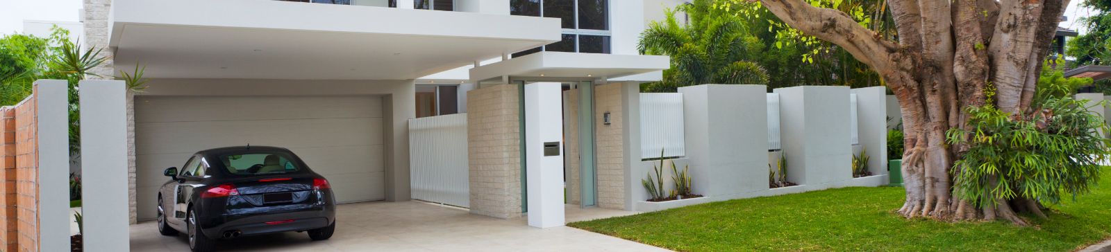 Sleek modern Antelope home with luxury car and automatic garage door under lush landscaping.