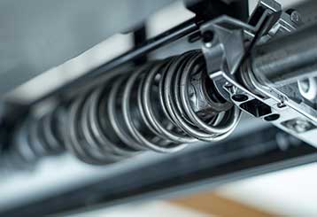 Close-up view of a heavy-duty torsion spring on a residential garage door in Antelope CA.