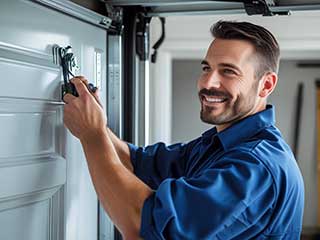 Garage door specialist in blue uniform performing service and repairs inside a residential Antelope garage.