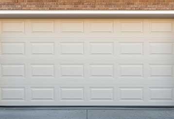 White overhead garage door fitted to a brick home, tightly sealed and freshly installed.