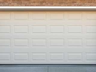 White overhead garage door fitted to a brick home, tightly sealed and freshly installed.