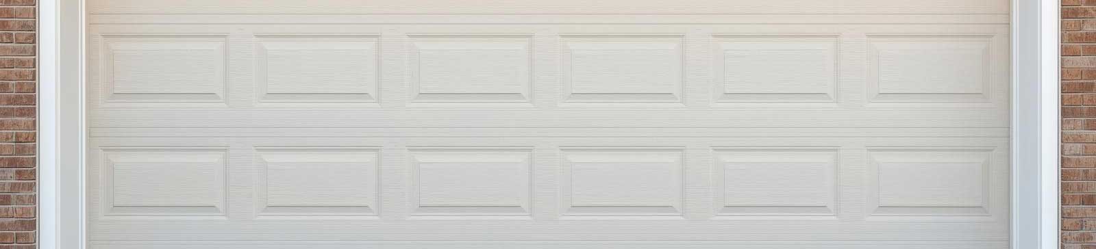 White overhead garage door fitted to a brick home, tightly sealed and freshly installed.
